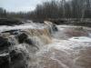 Muddy water pouring over shelves of rock