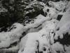 Boulders and water peaking through deep snow
